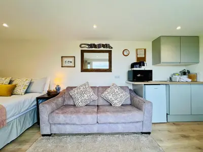 a living room with a couch and a kitchen at Romantic Cabin Retreat on 50-Acre Suffolk Farm in Burgh
