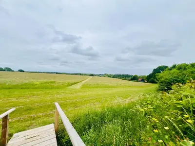 a field of green grass with a wooden fence at Romantic Cabin Retreat on 50-Acre Suffolk Farm in Burgh