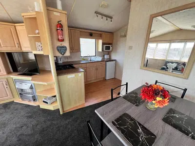 a kitchen with a table with a vase of flowers on it at Rohannah A&C Ultimate Caravan Retreat in East Mersea