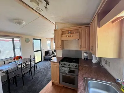 a kitchen and dining room with a table and a kitchen and a kitchen at Rohannah A&C Ultimate Caravan Retreat in East Mersea