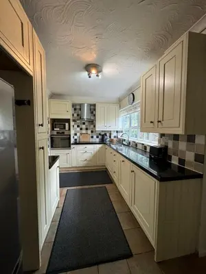 a kitchen with white cabinets and black counter tops at Sherrington Cottage 1 minute walk to Frintons blue flag beach Sleeps up to 8 in Frinton-on-Sea