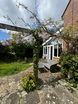 a bench in front of a house with flowers at Sherrington Cottage 1 minute walk to Frintons blue flag beach Sleeps up to 8 in Frinton-on-Sea