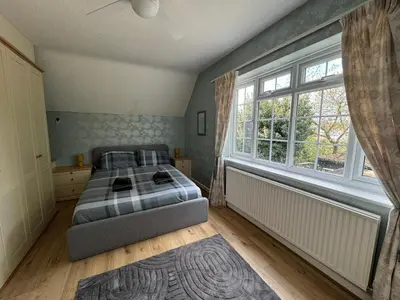 a bedroom with a bed and a large window at Sherrington Cottage 1 minute walk to Frintons blue flag beach Sleeps up to 8 in Frinton-on-Sea