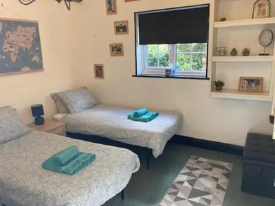 a living room with two beds and a window at Sherrington Cottage 1 minute walk to Frintons blue flag beach Sleeps up to 8 in Frinton-on-Sea