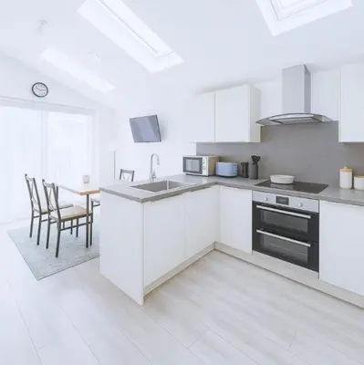 a kitchen with white cabinets and a table with chairs at Weekday Special - 4BDR House By Homestyles Hosts Short Lets & Serviced Accommodation Ipswich Near Town Centre With Free Parking in Ipswich