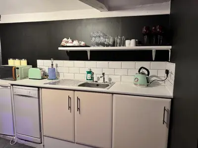 a kitchen with white cabinets and a sink at Essex Dungeon Suite in Heybridge