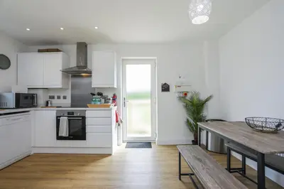 a kitchen with white cabinets and a wooden table at 8 Iris Cottage 4-BR Coastal Home in Suffolk in Wenhaston
