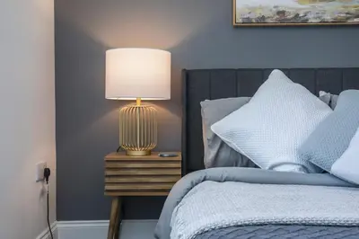 a bedroom with a bed with a lamp on a night stand at 8 Iris Cottage 4-BR Coastal Home in Suffolk in Wenhaston