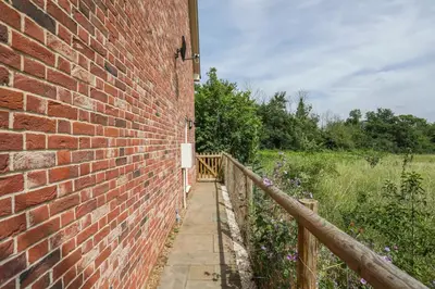 a brick wall next to a wooden fence at 8 Iris Cottage 4-BR Coastal Home in Suffolk in Wenhaston