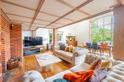 a living room with couches and a brick wall at Large indoor swimming pool in Thetford Forest - The Pool House in Downham