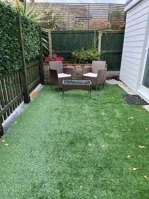 a backyard with two chairs and a table on grass at Dolly Studio in Colchester