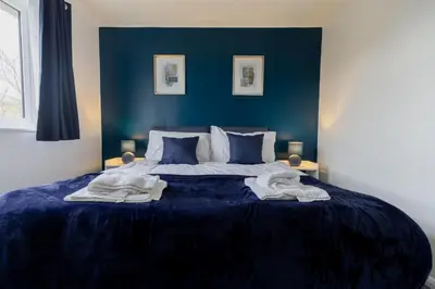 a blue bedroom with a large bed with blue walls at Cambridge House near Addenbrookes, station and parking! in Shelford