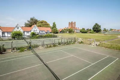 a tennis court in front of a house at 3 Bell Lodge - near Thorpeness Country Club and the beach - Aldeburgh Coastal Cottages in Thorpeness