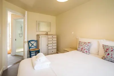 a bedroom with a white bed and a blue chair at 3 Bell Lodge - near Thorpeness Country Club and the beach - Aldeburgh Coastal Cottages in Thorpeness