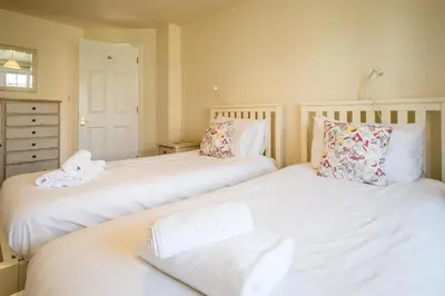 two beds in a bedroom with white sheets and pillows at 3 Bell Lodge - near Thorpeness Country Club and the beach - Aldeburgh Coastal Cottages in Thorpeness