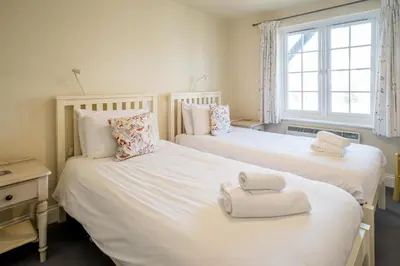 two twin beds in a room with a window at 3 Bell Lodge - near Thorpeness Country Club and the beach - Aldeburgh Coastal Cottages in Thorpeness