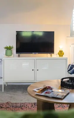 a living room with a large flat screen tv on a white cabinet at Gad About in Woodbridge