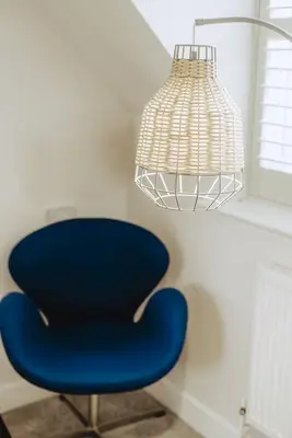 a blue chair sitting under a lamp with a light at Gad About in Woodbridge