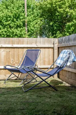 two lawn chairs sitting in the yard next to a fence at Gad About in Woodbridge