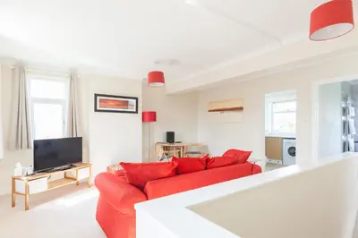 a living room with a red couch and a tv at Toothbrush Apartments - Ipswich East - Cauldwell Ave in Ipswich