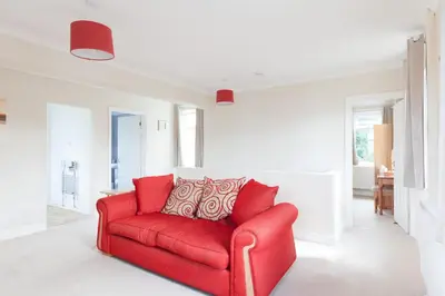 a red couch in a living room with red pillows at Toothbrush Apartments - Ipswich East - Cauldwell Ave in Ipswich