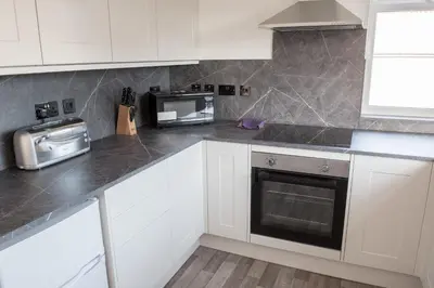 a kitchen with white cabinets and a microwave at Toothbrush Apartments - Ipswich East - Cauldwell Ave in Ipswich