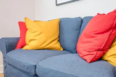 a blue couch with four colorful pillows on it at Goldfinch, Leiston in Leiston