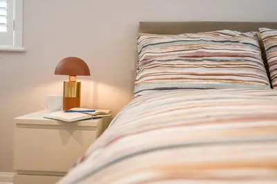 a bed with a lamp and a book on a night stand at Goldfinch, Leiston in Leiston