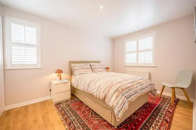 a bedroom with a bed with a rug and two windows at Goldfinch, Leiston in Leiston