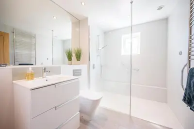 a white bathroom with a toilet and a shower at Goldfinch, Leiston in Leiston