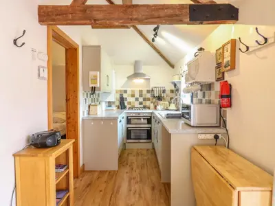 a small kitchen with white appliances and wooden floors at The Kiln in Harleston