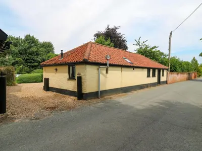a small white building with a red roof on a street at The Kiln in Harleston