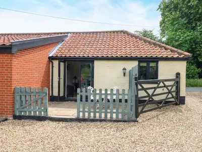 a small house with a gate and a brick building at The Kiln in Harleston