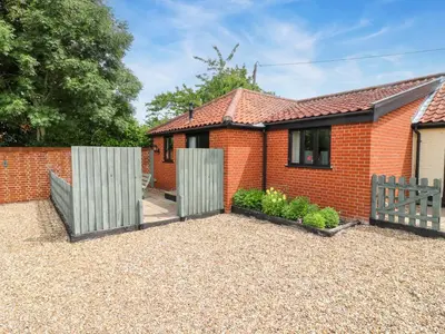 a red brick house with two wooden gates at The Golden Cross in Harleston