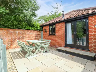 a patio with a table and chairs in front of a brick building at The Golden Cross in Harleston