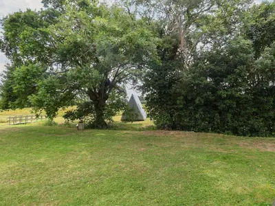 a tree and a triangular monument in a field at Oak Tree in Woodbridge