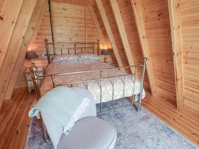 a bedroom with a bed in a log cabin at Oak Tree in Woodbridge