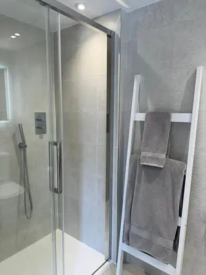 a shower with a glass door and a towel at Boutique Cottage by Bishop's Stortford train station, easy to Stansted Airport & Parking in Bishops Stortford