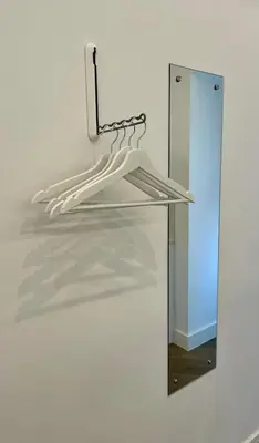 a mirror with hangers in front of a white wall at Boutique Cottage by Bishop's Stortford train station, easy to Stansted Airport & Parking in Bishops Stortford