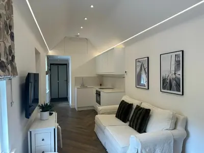 a living room with a white couch and a kitchen at Boutique Cottage by Bishop's Stortford train station, easy to Stansted Airport & Parking in Bishops Stortford