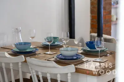 a wooden table with plates and wine glasses on it at Saltmarsh Cottage in Brightlingsea