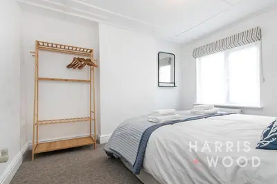 a white bedroom with a bed and two windows at Saltmarsh Cottage in Brightlingsea