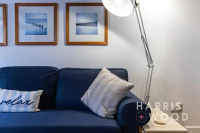 a blue couch with a pillow and a floor lamp at Saltmarsh Cottage in Brightlingsea