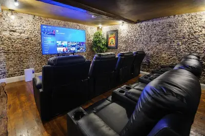 a cinema room with black leather chairs and a flat screen tv at Rock and Roll Suite In Manor House in Saffron Walden