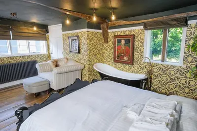 a bedroom with a bed and a chair at Rock and Roll Suite In Manor House in Saffron Walden
