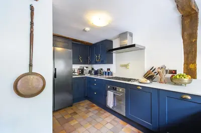 a kitchen with blue cabinets and a black refrigerator at Rock and Roll Suite In Manor House in Saffron Walden