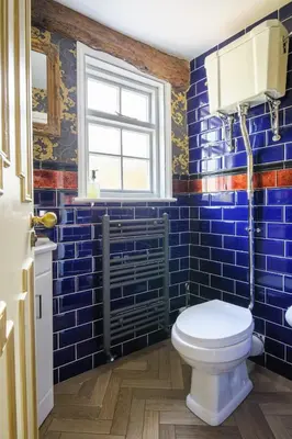 a bathroom with blue tiled walls and a toilet at Rock and Roll Suite In Manor House in Saffron Walden