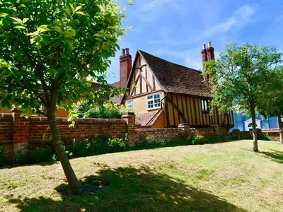 a house with a fence and a tree in front of it at Rock and Roll Suite In Manor House in Saffron Walden