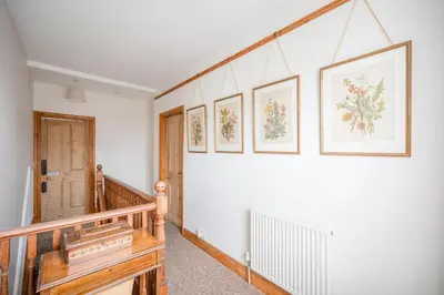 a hallway with a staircase with paintings on the wall at 45 Carr Avenue, Leiston in Leiston