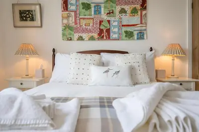 a bedroom with a white bed with two lamps at 45 Carr Avenue, Leiston in Leiston